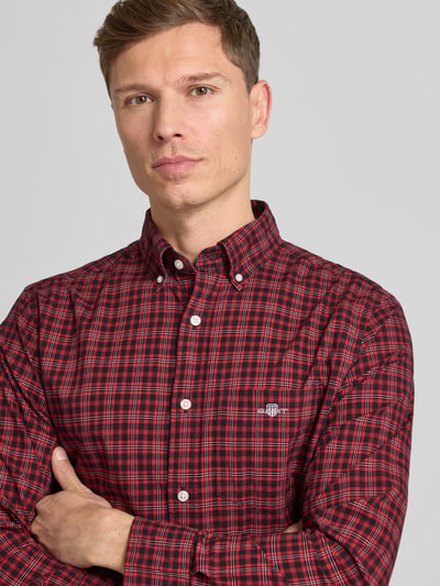 Männermodel draagt Vrijetijdsoverhemd met knoopsluiting van Gant in rood-zwart ruitpatroon, puur katoen, regular fit, borstzak, labelstitching, nahaufnahme oberkörper.