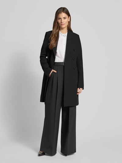Frauenmodel trägt Regular Fit Mantel mit Viskose-Anteil von Fuchs Schmitt in Schwarz, taillierte Passform, Reverskragen, doppelte Knopfleiste, Elastischer-Material-Mix, Ganzkörperansicht von vorne. Rückenlänge 94 cm, Schulterbreite 44 cm, Brustweite 48 cm, Ärmellänge 68 cm bei Größe 36.