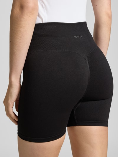 Männermodel trägt Radlerhose mit elastischem Bund Modell 'Shape Seamless' von aim'n, czarny, dopasowany krój, materiał z domieszką stretchu, Szerokość w rozmiarze S: 28 cm, długość nogawki wewnętrznej: 11 cm, detalaufnahme Rückansicht.