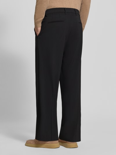 Männermodel trägt Stoffhose mit Bügelfalte Modell 'LEEK' van DRYKORN, zwart, materialmix met viscose, wide fit, achteraanzicht volledigheid.