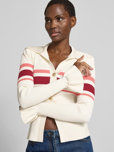 Frauenmodel trägt Strickjacke aus Viskose-Mix von Self-Portrait in Creme mit roten und rosa Streifen, Knopfleiste, geraffte Ärmelabschlüsse, eng anliegende Passform, Nahaufnahme Oberkörper.