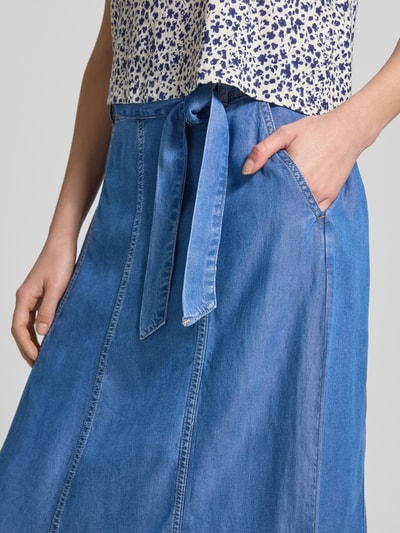 Frauenmodel trägt Midirock mit Bindegürtel Modell 'KOSMO' von B.Young in Denim-Optik mit Eingrifftaschen, Nahaufnahme Oberkörper.