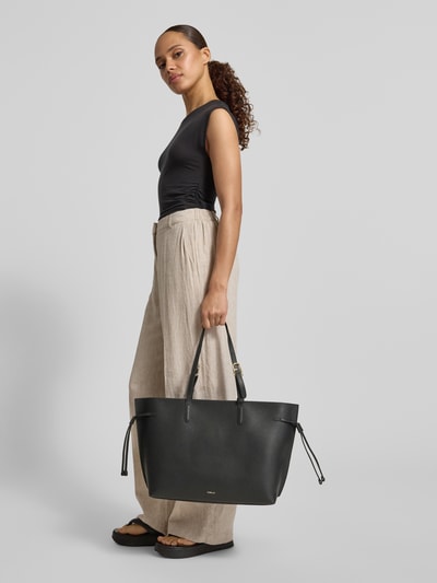 Frauenmodel trägt Shopper mit Label-Detail Modell 'AVA' von FURLA, schwarze Oberfläche, Hauptfach mit Reißverschluss, Tragehenkel, Ganzkörperansicht von vorne. Breite 50 cm, Länge 30 cm, Tiefe 15 cm, Länge Schulterriemen 60 cm.