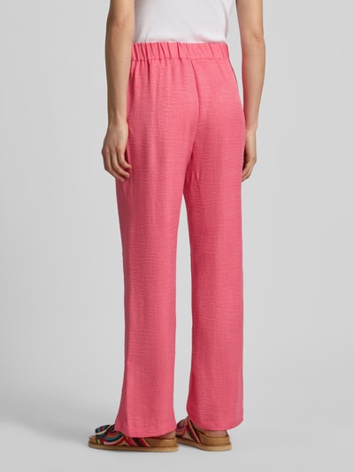 Frauenmodel trägt Hose in Denim-Optik Modell 'CHARISSA' von Soyaconcept, pink, elastischer Bund, strukturierte Oberfläche, Ganzkörperansicht Rückansicht. Damen Hose, Wide Leg, Bundweite 36 cm, Innenbeinlänge 75 cm, Größe S.