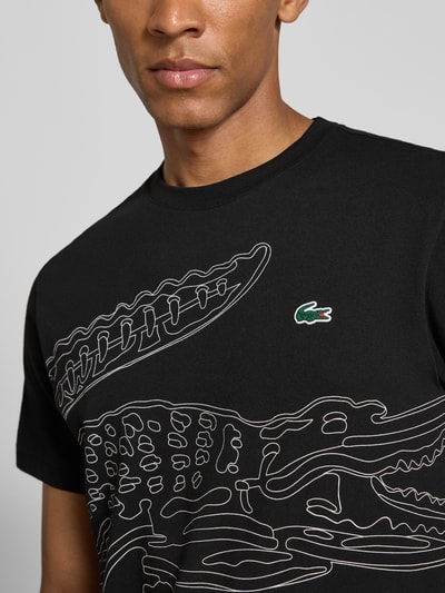 Mężczyzna nosi Regular Fit Sport-T-Shirt aus Baumwoll-Mix von Lacoste, czarny z białym nadrukiem i logo, Herren Sport-T-Shirt von Lacoste Sport, zbliżenie na górną część ciała