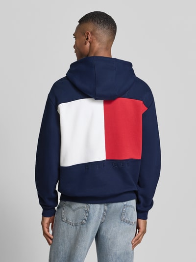Männermodel trägt Regular Fit Hoodie aus reiner Baumwolle von Tommy Hilfiger, Optik: Unifarben, Logo-Applikation, Ganzkörperansicht Rückansicht.