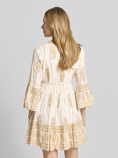 Frauenmodel trägt Minikleid mit Allover-Paisley-Print von Apricot in Creme mit goldenen Mustern, Viskose-Mix, taillierte Passform, Ganzkörperansicht Rückansicht.