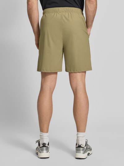 Männermodel trägt Shorts mit elastischem Bund Modell 'HALO AIR' von HALO, olivgrün, glatte Textur, Ganzkörperansicht Rückansicht. Herren Shorts, Material-Mix mit Stretch-Anteil, Regular Fit, Bundweite 40 cm, Innenbeinlänge 21 cm.