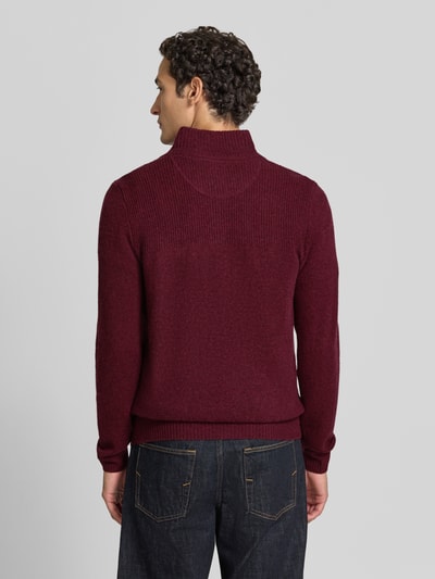 Männermodel trägt Regular Fit Strickpullover aus reiner Wolle von MCNEAL in Dunkelrot mit Troyer-Kragen, Ganzkörperansicht Rückansicht.