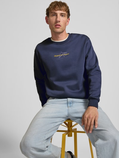 Männermodel trägt Regular Fit Sweatshirt aus Baumwoll-Mix mit Label-Detail von Alpha Industries in Dunkelblau, Nahaufnahme Oberkörper.
