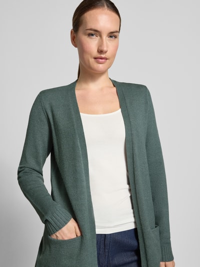 Frauenmodel trägt Strickjacke aus Viskose-Mix von VILA in dezentem Grün mit taillierter Passform, seitlichen Taschen, Nahaufnahme Oberkörper.