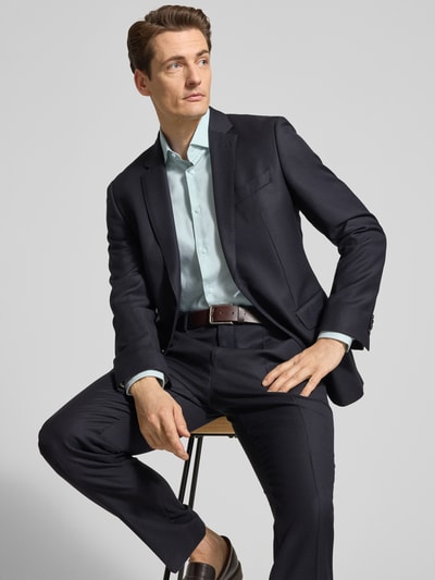 Männermodel trägt Slim Fit Freizeithemd aus Baumwoll-Mix von Tommy Hilfiger, jednolity kolor, melanż, krój slim fit, kołnierzyk typu kent, listwa guzikowa jednorzędowa, detal z logo, pas na plecach, długi rękaw, mankiety kombi, zaokrąglone wykończenie, popelina, mieszanka bawełny, Ganzkörperansicht von vorne
