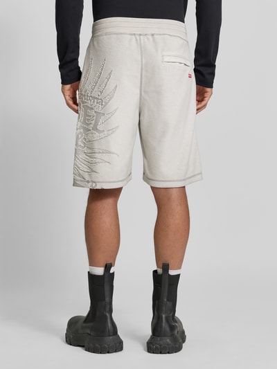 Männermodel trägt Straight Fit Shorts mit Baumwoll-Anteil von Diesel, hellgrauer Farbton, elastischer Bund, Logo-Detail, Gesäßtasche, Material-Mix, Bundweite 41 cm, Innenbeinlänge 23 cm, Ganzkörperansicht Rückansicht.