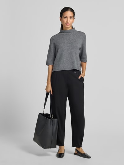 Frauenmodel trägt Regular Fit Hose mit Bundfalten Detail von MAC, unifarben, schwarze Webware, seitliche Eingrifftaschen, Ganzkörperansicht von vorne.