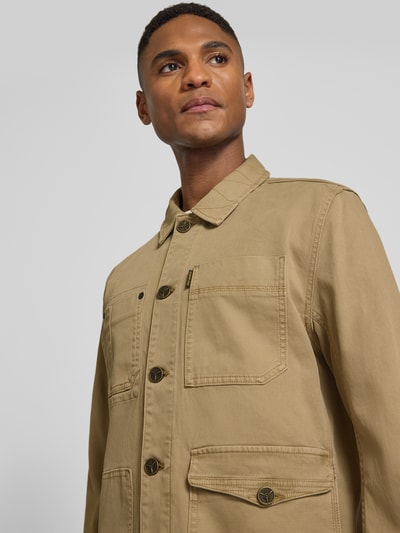 Męski model nosi Jeansjacke mit Eingriff- und Pattentaschen Modell 'FANCY' od PME Legend, bawełniany miks stretch, zapięcie na guziki, prosty krój, kolor beżowy, widoczne kieszenie, detal z logo, widok na górną część tułowia, z przodu.