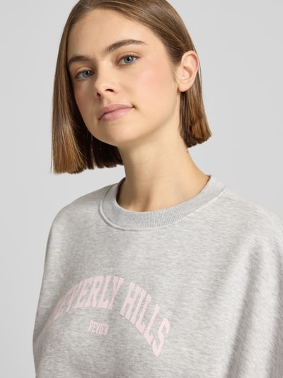 Frauenmodel trägt Sweatshirt mit Label-Print und Rundhalsausschnitt von Review aus Baumwoll-Mix im Relaxed-Fit, Nahaufnahme Oberkörper.