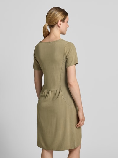 Frauenmodel trägt Relaxed Fit Kleid aus Viskose-Mix Modell 'Tara' von ZABAIONE in Oliv, Leinen-Viskose-Anteil, Kurzärmelig, Rückenlänge 96 cm, Brustweite 49 cm, Ärmellänge 21 cm, Ganzkörperansicht Rückansicht.