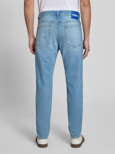 Mężczyzna nosi Straight Fit Jeans aus Baumwolle von HUGO Blue, jasnoniebieski, jednokolorowy, 5 kieszeni, detal z logo, średni stan, krój straight fit, widok całej sylwetki od tyłu.