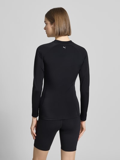 Frauenmodel trägt Badeshirt im langärmeligen Design Modell 'RASH GUARD' von PUMA, mieszanka materiałów z dodatkiem streczu, prosty krój, okrągły dekolt, nadruk z logo, uv-protection 50+, odporne na chlor, długość tyłu w rozmiarze S: 56 cm, czarny, gładka tekstura, Ganzkörperansicht Rückansicht.