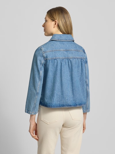 Frauenmodel trägt Regular Fit Jacke in Denim-Optik von Bash aus reiner Baumwolle, Umlegekragen, aufgesetzte Tasche, durchgängige Knopfleiste, Rückenlänge 52 cm, Schulterbreite 38 cm, Brustweite 49 cm, Ärmellänge 53 cm, Jeansblau, strukturierte Oberfläche, Ganzkörperansicht Rückansicht.