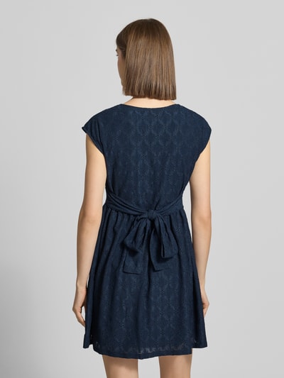 Frauenmodel trägt Kurzes Kleid mit V-Ausschnitt, Lochstickerei und großer Schleife von REVIEW, Dunkelblau, A-Linie, Material-Mix mit Stretch-Anteil, Rückenlänge 84 cm, Brustweite 42 cm, Ganzkörperansicht Rückansicht.