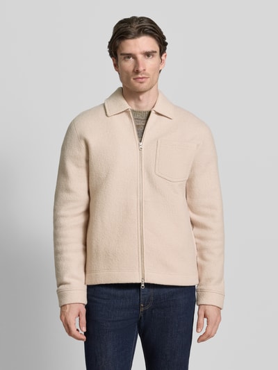 Männermodel trägt cremefarbene Regular Fit Hemdjacke aus reiner Wolle Modell 'HANNES' von Samsøe Samsøe mit Kentkragen und Reißverschluss, Ganzkörperansicht von vorne.