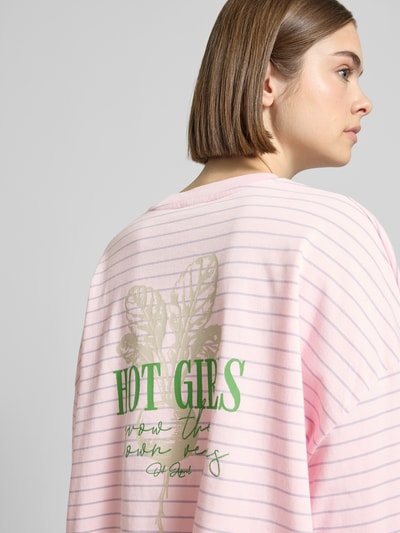 Frauenmodel trägt Longsleeve mit rückseitigem Statement-Print von OH APRIL in Rosa mit weißen Streifen, Reine Baumwolle, Loose-Fit, Rundhalsausschnitt, Rückenlänge 53 cm bei Größe S, Ganzkörperansicht Rückansicht.
