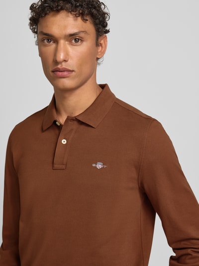 Männermodel trägt Regular Fit Poloshirt mit Label-Stitching von Gant in Braun, Reine Baumwolle, Polokragen, Knopfleiste, Nahaufnahme Oberkörper.