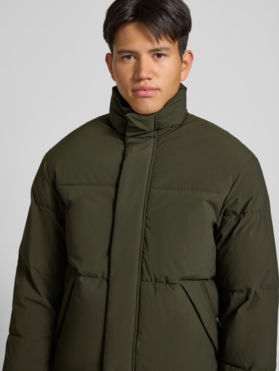 Männermodel trägt Steppjacke mit verdecktem Reißverschluss Modell 'SOHO' von JACK & JONES, olivgrün, glatte Oberfläche, Nahaufnahme Oberkörper. Rückenlänge 70 cm, Schulterbreite 47 cm, Brustweite 60 cm, Ärmellänge 68 cm, Regular Fit, Stehkragen.
