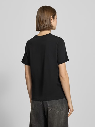Frauenmodel trägt Regular Fit T-Shirt aus reiner Baumwolle Modell 'RIA' von Pieces, Optik: Unifarben in Schwarz, Feinripp-Struktur, Kurzarm mit fixiertem Umschlag, Ganzkörperansicht Rückansicht.