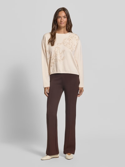Vrouwenmodel draagt Sweatshirt mit Stitchings und Pailletten van Milano Italy in crèmekleur, regular fit, ronde hals, modal-mix met stretch, lange mouwen, bruine broek, voorkant volledig zichtbaar, Ganzkörperansicht von vorne.