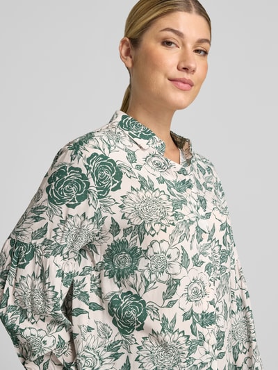Kobiece model nosi bluzka z czystej wiskozy od Christian Berg Woman, luźny krój, listwa guzikowa, długie rękawy, elastyczne ściągacze na rękawach, kremowy kolor w zielone kwiaty, tekstura gładka, długość tyłu w rozmiarze 36: 70 cm, długość rękawów w rozmiarze 36: 60 cm, zbliżenie na górną część ciała, widok z przodu.
