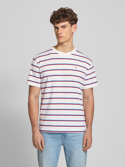 Männermodel trägt Regular Fit T-Shirt aus reiner Baumwolle von Tommy Jeans, Optik:Allover-Muster, gestreift, Ganzkörperansicht von vorne.