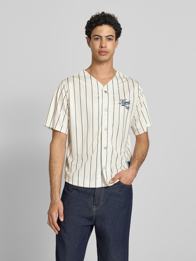 Männermodel trägt Regular Fit Freizeithemd mit Logo-Stitching von KARL KANI, creme mit dunkelblauen Streifen, V-Ausschnitt, Knopfleiste, Kurzärmelig, Rückenlänge 64 cm, Schulterbreite 45 cm, Ärmellänge 27 cm, Ganzkörperansicht von vorne.