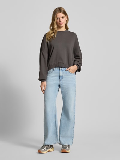 Frauenmodel trägt Oversized Sweatshirt mit Label-Stitching von OH APRIL in Dunkelgrau, reine Baumwolle, Rundhalsausschnitt, Ganzkörperansicht von vorne.