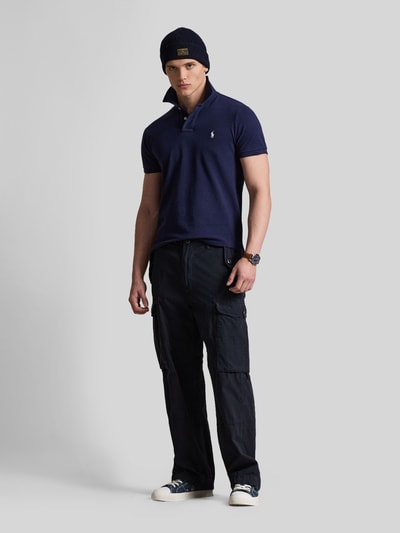 Männermodel trägt Regular Fit Poloshirt aus reiner Baumwolle von Polo Ralph Lauren in Dunkelblau, unifarben, Kurzarm, Piqué, Ganzkörperansicht von vorne.