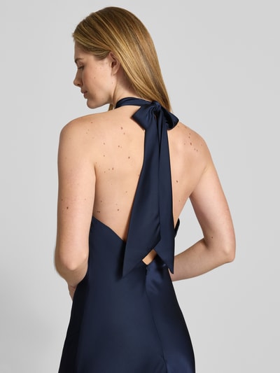 Frauenmodel trägt Abendkleid mit Neckholder zum Binden von Mascara aus dunkelblauem Satin, körpernahe Passform, Rückenausschnitt, Maxilänge, Rückseitiger Nahtreißverschluss, Rückenlänge bei Größe 36: 160 cm, Brustweite bei Größe 36: 42 cm, Detailaufnahme Rückansicht.