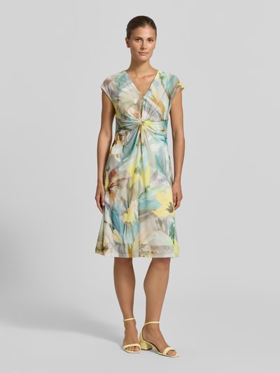 Frauenmodel trägt Minikleid mit V-Ausschnitt und Knotendetail von Betty Barclay, Material-Mix mit Stretch-Anteil, Taillierter Schnitt, Allover-Look, florale Farben, glatte Textur, Ganzkörperansicht von vorne.