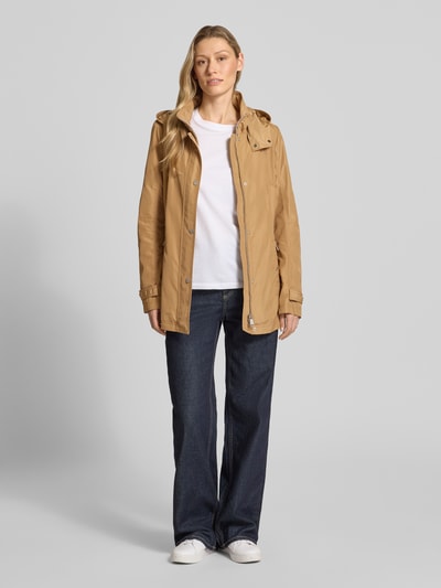 Vrouwenmodel draagt Regular Fit Jacke mit Logo-Print van Fuchs Schmitt in lichtbruin, met opstaande kraag, capuchon met tunnelkoord, ritszakken, lengte 71 cm, schouderbreedte 40 cm, borstwijdte 51 cm, mouwlengte 66 cm; volle lichaamsweergave van voren.