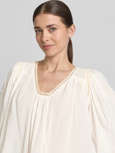Frauenmodel trägt Cropped Bluse mit 3/4-Arm Modell 'ISMARA' von Drykorn aus Baumwoll-Viskose-Mix in Creme mit V-Ausschnitt, Nahaufnahme Oberkörper.
