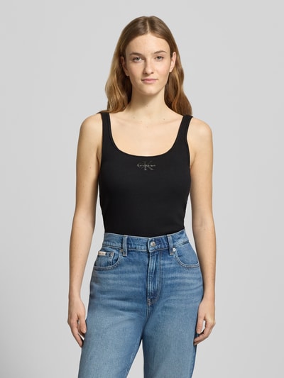 Kobiece modelka nosi Slim Fit Top mit Logo-Print Modell 'Scoop' od Calvin Klein Jeans, czarny, okrągły dekolt, krój slim fit, długość tyłu 42 cm w rozmiarze S, przód w całości.