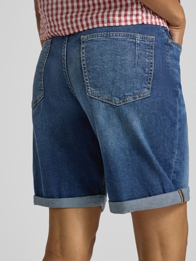 Kobiece modelka nosi Regular Fit Jeansshorts aus Baumwoll-Mix Modell 'SURI' von s.Oliver RED LABEL w stylu denim, widok tyłu całej sylwetki.