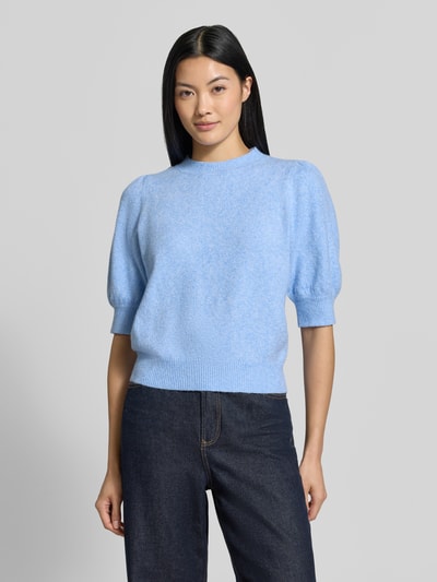 Frauenmodel trägt Regular Fit Pullover mit Puffärmeln von VERO MODA in Hellblau zu dunkler Jeans, weiche Textur, Ganzkörperansicht von vorne.