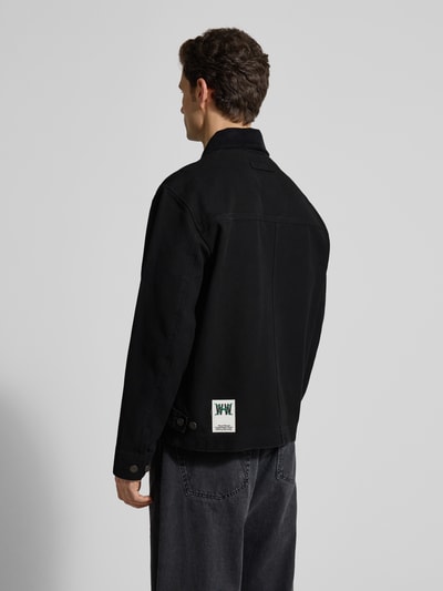 Männermodel trägt schwarze Jacke mit Zweiwege-Reißverschluss Modell 'Bo' von Wood Wood aus Baumwolle, lockerer Schnitt, Rückenansicht.