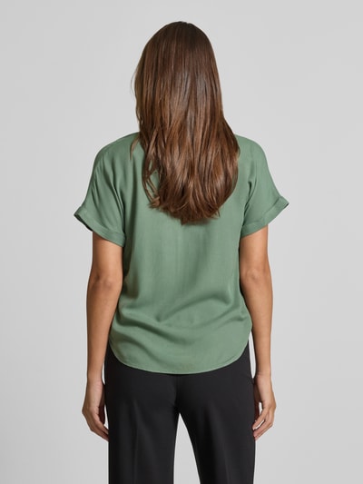 Frauenmodel trägt Relaxed Fit Blusenshirt aus reiner Viskose Modell 'BEAUTY' von Vero Moda in Uni-Optik, Tunika-Kragen, V-Ausschnitt, kurze Ärmel mit fixiertem Umschlag, abgerundeter Abschluss, grüne Farbe, glatte Textur, Ganzkörperansicht Rückansicht.
