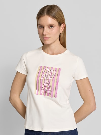 Frauenmodel trägt T-Shirt mit Motiv-Print und Rundhalsausschnitt von Zero, gerader Schnitt, cremefarbener Stoff mit rosa-gelbem Print, Ganzkörperansicht von vorne.
