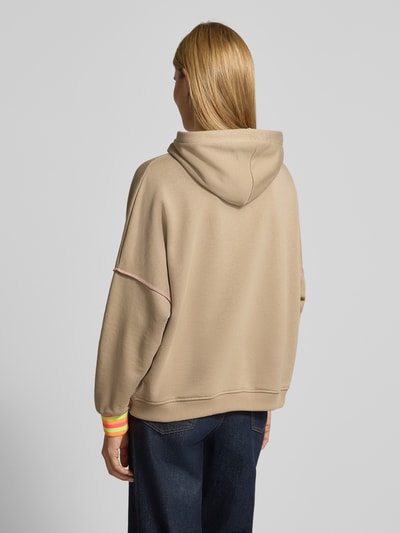 Frauenmodel trägt Oversized Hoodie mit Statement-Print von miss goodlife in Beige, Kapuze, bunte Bündchen, reine Baumwolle, Rückansicht Ganzkörperansicht.