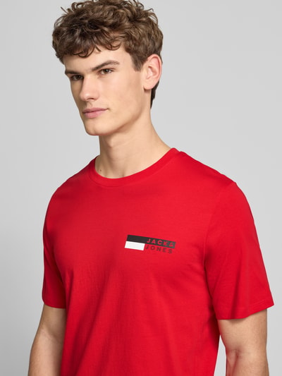 Męski model nosi T-Shirt z label-print model 'CORP' od JACK & JONES, czerwony kolor, bawełna, prosty krój, zbliżenie na górę ciała.