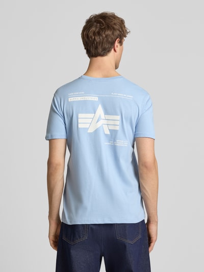 Männermodel trägt T-Shirt mit Label-Patch von Alpha Industries aus reiner bawełna, prosty krój, okrągły dekolt, długość tyłu 66 cm, Ganzkörperansicht Rückansicht