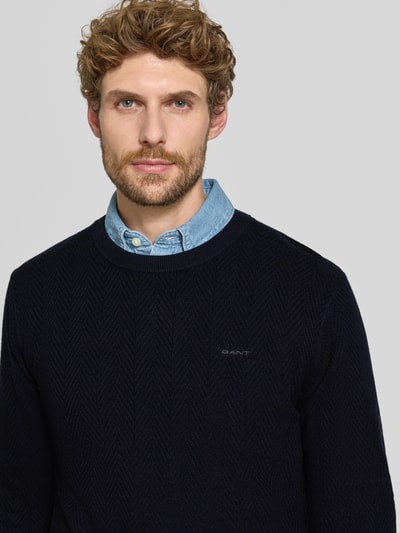 Männermodel trägt Regular Fit Pullover aus Baumwoll-Woll-Mix von GANT in Dunkelblau auf glattem Hintergrund, Nahaufnahme Oberkörper. Herren Pullover von GANT